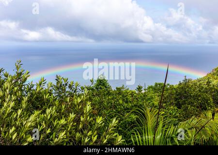 Farbenprächtiger Regenbogen über der Praslin Island mit tropischem Regenwald, azurblauem Ozean vom Mont Azore auf den Seychellen aus gesehen. Stockfoto