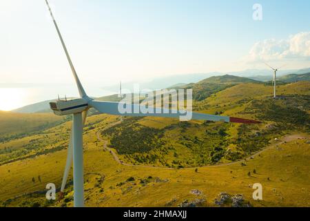 Windmühlen mit großen Rotorblättern erzeugen sauberen Strom, der auf einer Station im wilden Hochland in der Nähe der Adria für den Umweltschutz aus der Luft betrieben wird Stockfoto