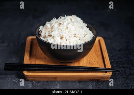 Basmati-Reis, gekocht und roh in verschiedenen Schüsseln und auf verschiedenen Hintergründen platziert. Gesundes Wohnkonzept. Stockfoto