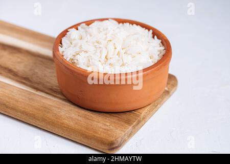 Basmati-Reis, gekocht und roh in verschiedenen Schüsseln und auf verschiedenen Hintergründen platziert. Gesundes Wohnkonzept. Stockfoto
