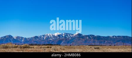 Panoramablick auf die San Gabriel Mountains in Südkalifornien mit spätem Winterschnee von der Mojave-Wüste aus gesehen Stockfoto