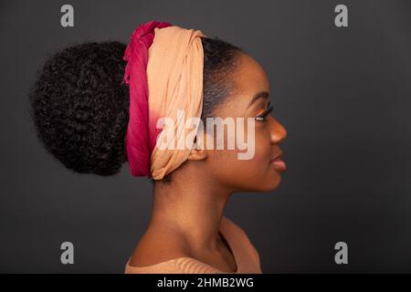 Ein Nahaufnahme-Porträt einer schwarzen Frau mit gefesselten Haaren und einem Haarband. Stockfoto