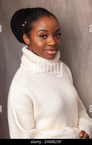 Eine schöne junge schwarze Frau, die einen weißen Rollkragenpullover trägt. Stockfoto