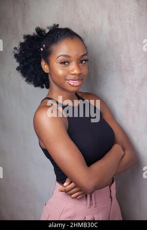 Porträt einer jungen schwarzen Frau, die mit gekreuzten Armen steht. Stockfoto