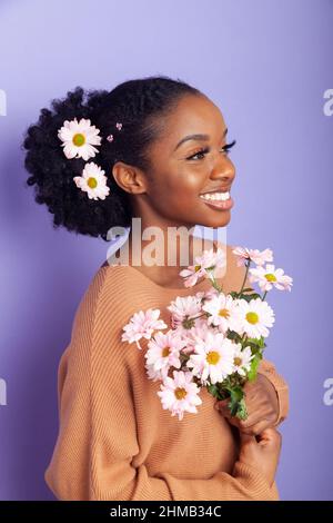 Eine schwarze Britin mit Blumen in ihrem gefesselten Hinterhaar. Stockfoto