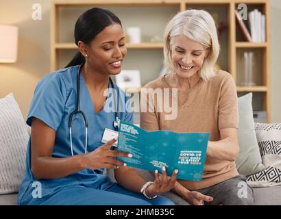 Den Impfstoff oder das Virus zu bekommen... Ihre Wahl. Aufnahme eines Arztes, der eine Broschüre über Covid-19 auf dem Sofa zu Hause liest. Stockfoto