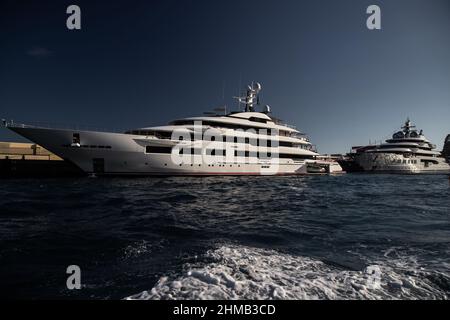 Zwei riesige Yacht im Hafen von Monaco bei Sonnenuntergang, glänzende Bord des Motorbootes, der verchromte Handlauf, Megayacht ist in der Marina vertäut, Sonnenreflexion Stockfoto