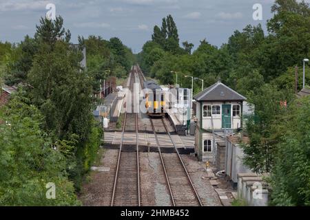 East Midlands Züge der Klasse 156 Sprinter Train 156405 am Bahnhof Lowdham (östlich von Nottingham) mit Bahnübergang und geschlossenem Signalkasten Stockfoto