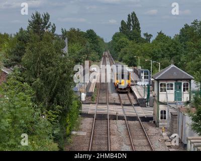 East Midlands Züge der Klasse 156 Sprinter Train 156405 am Bahnhof Lowdham (östlich von Nottingham) mit Bahnübergang und geschlossenem Signalkasten Stockfoto