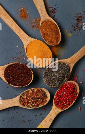 Holzlöffel mit aromatischen Gewürzen auf dunklem Hintergrund, Nahaufnahme Stockfoto