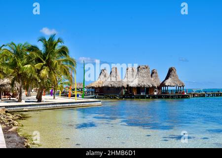 Blick auf einige strohgedeckte Hütten im tahitischen Stil entlang eines Piers in einem Strandresort in San Pedro, Belize. Stockfoto