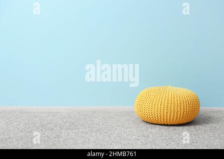 Gelber Puff auf grauem Teppich in der Nähe der blauen Wand Stockfoto