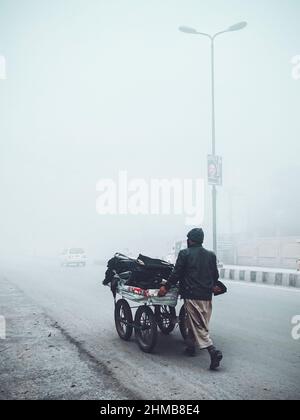 Foto eines armen Mannes, der vor dem Regen mit seinem Vorrat im schweren Nebel läuft Stockfoto
