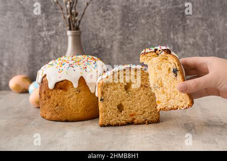 Frau hält ein Stück leckeren Osterkuchen auf grauem Hintergrund Stockfoto