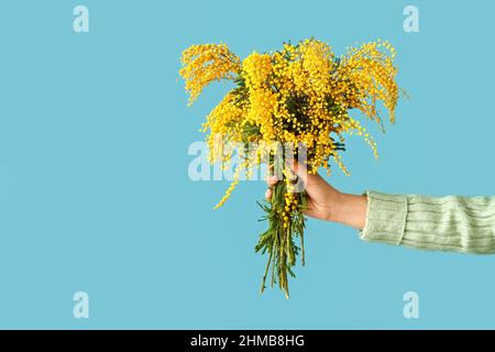 Frau hält Bouquet von Mimosen Blumen auf farbigem Hintergrund Stockfoto