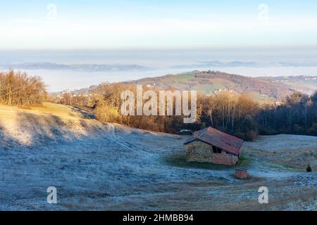 Landschaft der Appennini-Berge mit ländlichem Gebäude, Italien, im Hintergrund die Ebene, die vom Nebel bedeckt ist Stockfoto