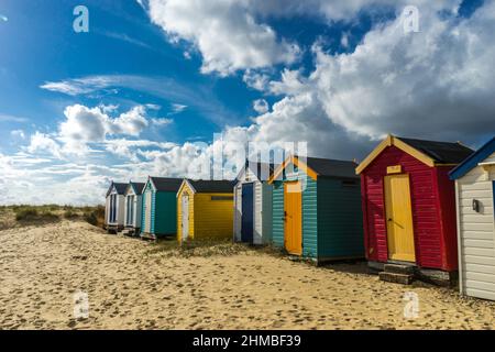 Reihe von Strandhütten in Southwold, Suffolk, England unter einem dramatischen Sommerhimmel Stockfoto