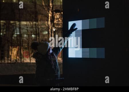 Toronto, Kanada. 07th. Februar 2022. Eine Frau nutzt ihre Hand, um mit einer Lichtkunst-Installation ‘Control No Control' von Studio Iregular zu interagieren, einem großen LED-Würfel, der auf alles reagiert, was ihn berührt, und jede Bewegung, die auf seiner Oberfläche durchgeführt wird. Eine Ausstellung nordischer und kanadischer Lichtkunst im Toronto Harbourfront Centre, die gemeinsam mit Fjord Studio produziert wurde. Kredit: SOPA Images Limited/Alamy Live Nachrichten Stockfoto