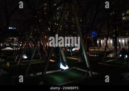 Toronto, Kanada. 07th. Februar 2022. Die Menschen spielen mit einer Lichtkunstinstallation im Freien, dem ‘Sense Light Swing' des Künstlers Alexander Lervik, einer Leuchte, die nach dem Vorbild einer hängenden Schaukel für Kinder gestaltet wurde.die Nordic Lights Outdoor-Winterausstellung, eine Ausstellung nordischer und kanadischer Lichtkunst im Toronto Harbourfront Center, die gemeinsam mit Fjord Studio produziert wurde. (Foto von Katherine Cheng/SOPA Images/Sipa USA) Quelle: SIPA USA/Alamy Live News Stockfoto