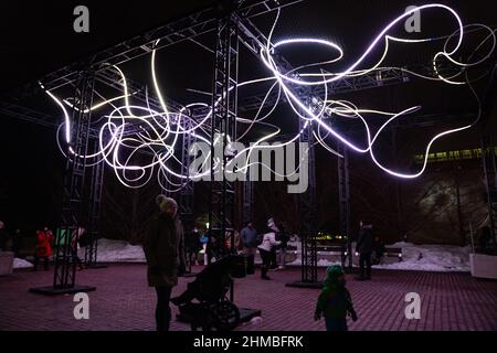 Toronto, Kanada. 07th. Februar 2022. Eine Mutter und ein Kind, die bei einer Außenkunstinstallation ‘Pressure' von Hans E. Madsen und Frederik D. Hougs zu sehen sind, ein Stück, das aus einer 300 Meter langen, pulsierenden RGB-LED-Lichterkette besteht, die einem Doodle ähnelt und um eine große Konstruktion gewickelt ist. Die Nordic Lights Outdoor-Winterausstellung ist eine Ausstellung nordischer und kanadischer Lichtkunst im Toronto Harbourfront Centre, die gemeinsam mit Fjord Studio produziert wurde. (Foto von Katherine Cheng/SOPA Images/Sipa USA) Quelle: SIPA USA/Alamy Live News Stockfoto