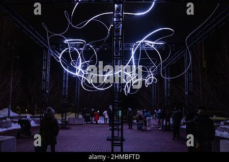 Toronto, Kanada. 07th. Februar 2022. Menschen, die bei einer Außenkunstinstallation, ‘Pressure' von Hans E. Madsen und Frederik D. Hougs, gesehen wurden, ein Stück, bestehend aus einer 300 Meter langen Kette von pulsierenden RGB-LED-Lichtern, die einem Kritzeln ähneln und um eine große Konstruktion gewickelt sind. Die Nordic Lights Outdoor-Winterausstellung ist eine Ausstellung nordischer und kanadischer Lichtkunst im Toronto Harbourfront Centre, die gemeinsam mit Fjord Studio produziert wurde. (Foto von Katherine Cheng/SOPA Images/Sipa USA) Quelle: SIPA USA/Alamy Live News Stockfoto