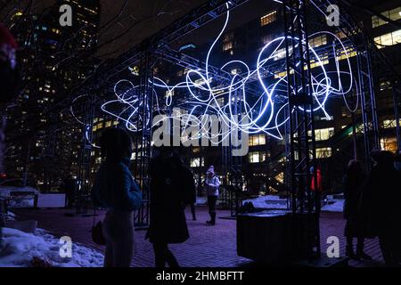 Toronto, Kanada. 07th. Februar 2022. Die Menschen blicken auf eine Kunstinstallation im Freien, ‘Pressure' von Hans E. Madsen und Frederik D. Hougs, ein Stück, das aus einer 300 Meter langen Kette pulsierender RGB-LED-Leuchten besteht, die einem Kritzeln ähneln und um eine große Konstruktion gewickelt sind. Die Nordic Lights Outdoor-Winterausstellung ist eine Ausstellung nordischer und kanadischer Lichtkunst im Toronto Harbourfront Centre, die gemeinsam mit Fjord Studio produziert wurde. (Foto von Katherine Cheng/SOPA Images/Sipa USA) Quelle: SIPA USA/Alamy Live News Stockfoto