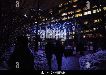 Toronto, Kanada. 07th. Februar 2022. Die Menschen gehen aus einer Außenkunstinstallation ‘Pressure' von Hans E. Madsen und Frederik D. Hougs, einer Arbeit, die aus einer 300 Meter langen Kette pulsierender RGB-LED-Leuchten besteht, die einem Kritzeln ähneln und um eine große Konstruktion gewickelt sind. Die Nordic Lights Outdoor-Winterausstellung ist eine Ausstellung nordischer und kanadischer Lichtkunst im Toronto Harbourfront Centre, die gemeinsam mit Fjord Studio produziert wurde. (Foto von Katherine Cheng/SOPA Images/Sipa USA) Quelle: SIPA USA/Alamy Live News Stockfoto