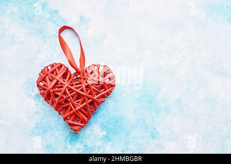 Rotes Korbherz auf einem Hintergrund mit blauer Himmelsimitation. Platz für Text kopieren, Draufsicht. Valentinstag-Konzept Stockfoto