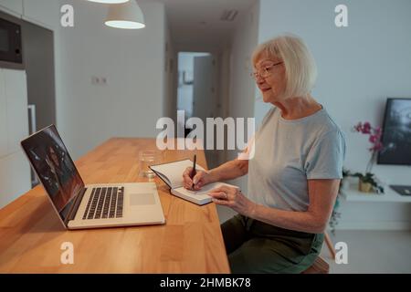 Ältere Frau mit Laptop, während sie zu Hause sitzt Stockfoto