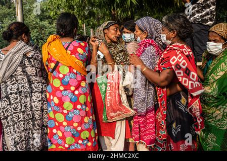 Eine Gruppe von Frauen, die sich in der Schlange aufstellten, um Nahrungsmittel zu erhalten, die eine lokale Organisation auf den Straßen von Dhaka verteilt.85 % der wirtschaftlich aktiven Bevölkerung des Landes sind im informellen Sektor ohne jegliche soziale Sicherheit beschäftigt, Dieser Sektor war aufgrund der Schließung vieler Aktivitäten und der limitierten Bewegungen der am stärksten von der Pandemie geschädigte Sektor. Stockfoto