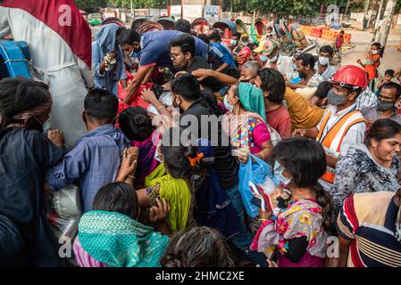 Die armen Menschen kämpfen darum, die Nahrungsmittel zu erhalten, die eine kleine lokale Organisation auf den Straßen von Dhaka verteilt.85 % der wirtschaftlich aktiven Bevölkerung des Landes sind im informellen Sektor ohne jegliche soziale Sicherheit beschäftigt, Dieser Sektor war aufgrund der Schließung vieler Aktivitäten und der limitierten Bewegungen der am stärksten von der Pandemie geschädigte Sektor. Stockfoto