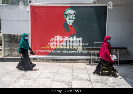 Dhaka, Bangladesch. 24th April 2021. Frauen gehen an einem Transparent am Eingang der Pflegeeinrichtung vorbei. Jeden Tag wird eine große Anzahl von Leichen aus dem DCNN in Dhaka entfernt, einem Markt, den die Regierung als COVID-19-Notfallzentrum für die Versorgung von Patienten adaptierte, insbesondere während der Monate der zweiten Infektionswelle in Bangladesch und dem „indischen Subkontinent“. (Foto von Israel Fuguemann/SOPA Images/Sipa USA) Quelle: SIPA USA/Alamy Live News Stockfoto