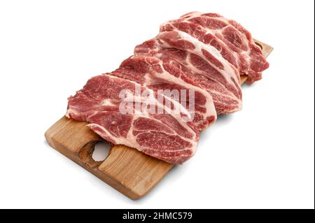 Rohes Schweinefleisch in Scheiben geschnitten auf Holzbrett auf weißem Hintergrund. Haufen von Stücken rohes Schweinefleisch. Frisches rohes Rindfleisch Lamm auf weiß isoliert. Haufen roher Steaks Stockfoto