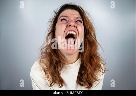 Nahaufnahme Porträt einer verrückten Frau in Zwangsjacke auf weißem Hintergrund. Stockfoto