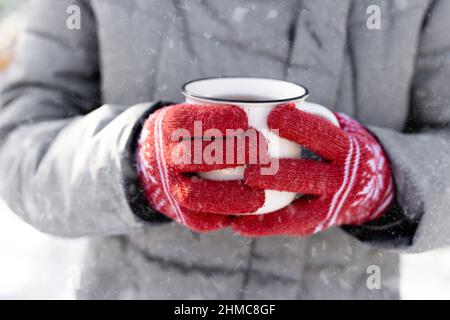 Hände in Handschuhen, die den Becher halten Stockfoto