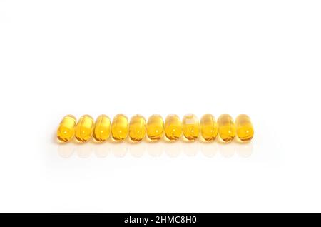 Viele gelbe Omega-3-Fischöl-Kapseln liegen in einer Reihe Stockfoto
