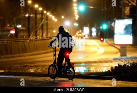 Rostock, Deutschland. 09th. Februar 2022. Ein Radfahrer fährt die fast leere Straße vor dem Hauptbahnhof entlang. Die Infektionszahlen steigen, aber gleichzeitig gewinnt die Diskussion über Entspannung weiter an Dynamik. Quelle: Bernd Wüstneck/dpa-Zentralbild/dpa/Alamy Live News Stockfoto