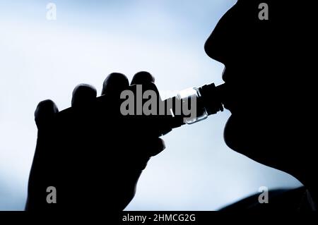 PRODUKTION - 07. Februar 2022, Baden-Württemberg, Bösingen: ILLUSTRATION - Eine junge Frau raucht mit einer E-Shisha in ihrer Wohnung und wird als Silhouetten gesehen. Foto: Silas Stein/dpa Stockfoto