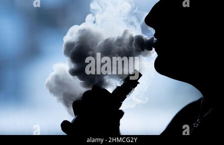 PRODUKTION - 07. Februar 2022, Baden-Württemberg, Bösingen: ILLUSTRATION - Eine junge Frau raucht mit einer E-Shisha in ihrer Wohnung und wird als Silhouetten gesehen. Foto: Silas Stein/dpa Stockfoto