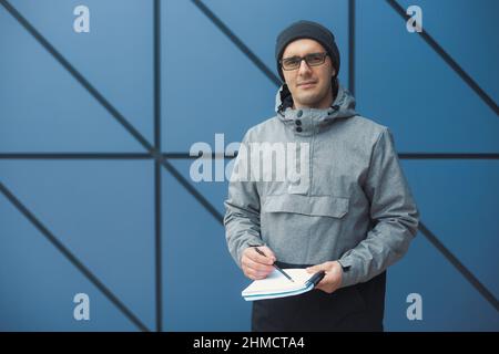 Nahaufnahme Porträt eines hübschen 30-35 Jahre alten Mannes im Freien, der in der Nähe der Wand steht Stockfoto