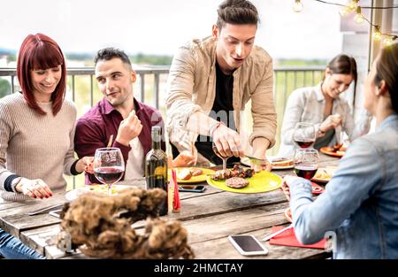 Multikulturelle Freunde essen zusammen auf der Dachparty zur Happy Hour in der Freiluftvilla - Junge Leute trinken Wein auf der Terrasse des Restaurants - Lif Stockfoto