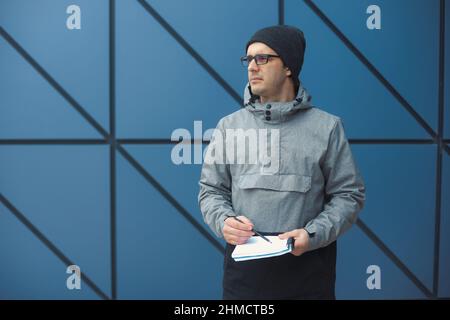 Nahaufnahme Porträt eines hübschen 30-35 Jahre alten Mannes im Freien, der in der Nähe der Wand steht Stockfoto
