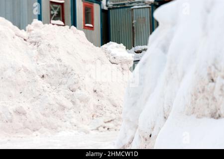 Riesige Schneeverwehungen im Vordergrund und Metallbehälter im verschwommenen Hintergrund, Winterszene Stockfoto