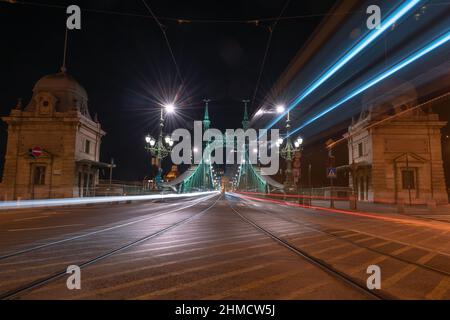 Leichte Wege von Fahrzeugen auf der Freiheitsbrücke bei Nacht in Budapest, Ungarn