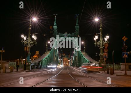 Leichte Wege von Fahrzeugen auf der Freiheitsbrücke bei Nacht in Budapest, Ungarn Stockfoto