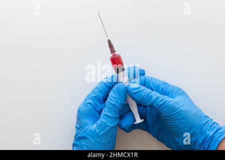 Draufsicht auf Frauenhände in medizinischen Handschuhen, die den Spritzenkörper mit der Vitamingruppe B zur Injektion auf weißem Hintergrund halten Stockfoto