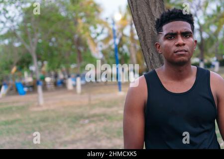 Afroamerikanischer Mann im Park, der sich an den Baum lehnt Stockfoto