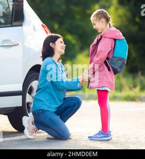 Lächelnde Mutter bringt Tochter zur Schule Stockfoto