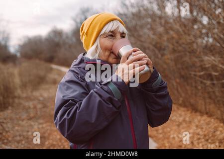 Ältere Frau Reisende mit Thermoskanne in der Stadt Reisende in der schönen Natur. Zero Waste Eco-Konzept Stockfoto