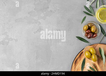 Flatlay Zusammensetzung aus Oliven und Olivenöl auf grauem Hintergrund Stockfoto